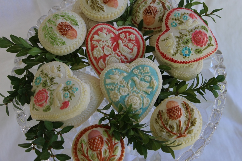 Colorful springerle cookies arranged on a plate with greens.