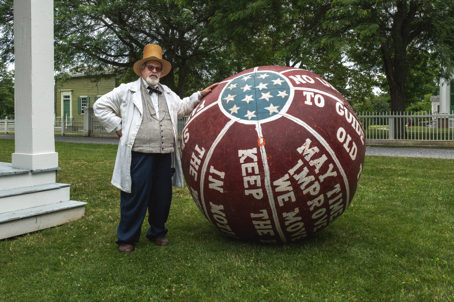 A man in historic clothing standing next to a giant red, white, and blue ball.